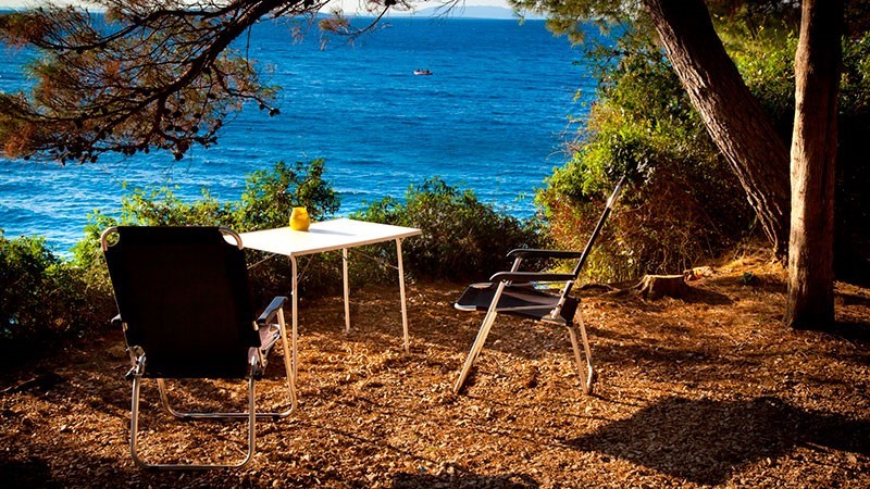 Zwei Stühle und ein Tisch mit Blick auf das Meer an einem sonnigen Tag