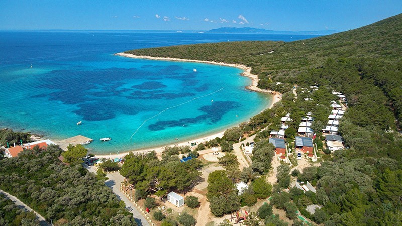 Luftaufnahme eines Küstengebiets mit türkisfarbenem Wasser und üppigem Grün auf der Insel Cres