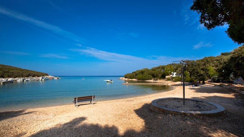 Spokojna plaża z czystą niebieską wodą i ławką pod słonecznym niebem