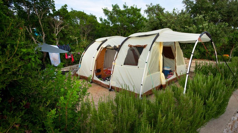 Ein großes Campingzelt auf einem üppig grünen Campingplatz